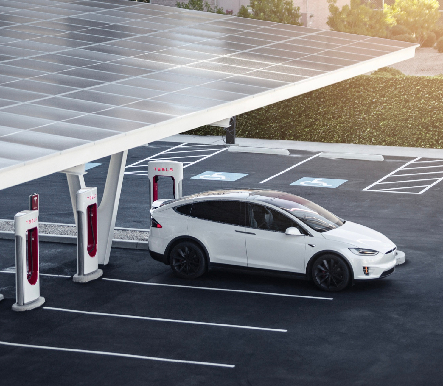 A white Tesla charges up at Superchargers