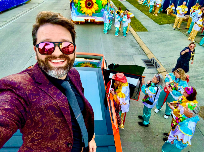 Mr. Moonbeam's Tesla Cybertruck in pristine condition, rolling as a marshal vehicle in the Krewe of Orpheus Mardi Gras parade, March 3, 2025, before the attacks, with Mardi Gras decorations and marshals visible in the background