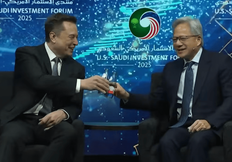 (Elon and Jensen raise their water bottles and clink them in a playful toast, drawing laughter and applause from the audience.)