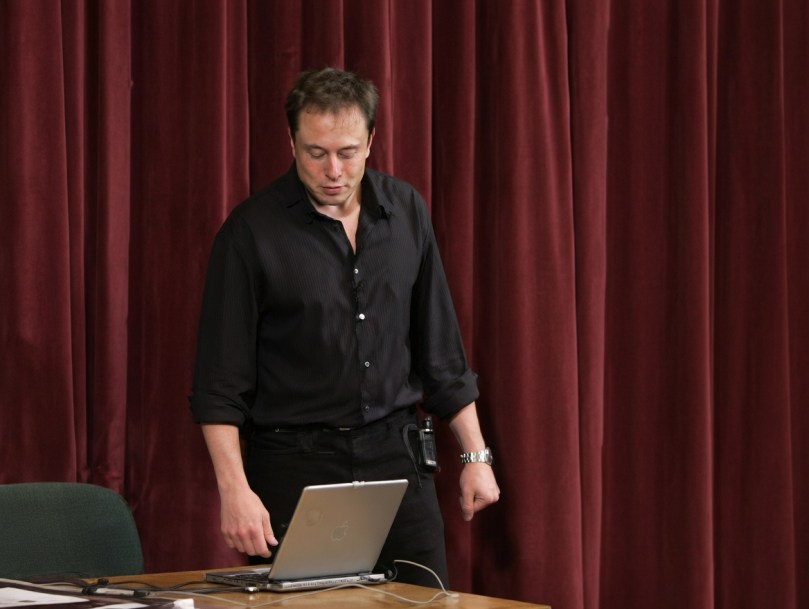 Elon Musk at 32 presenting at Stanford University – October 2003 Entrepreneurial Thought Leaders Series - Elon Musk stands at the podium during his rarely seen 2003 Stanford talk. At the time, SpaceX was only one year old and no Falcon rocket had flown yet. Screen grab from the original recording, enhanced for clarity by Grok Imagine.