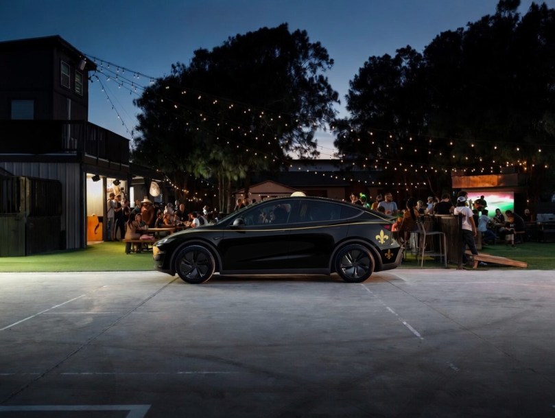 Black Tesla Model Y with elegant gold Mardi Gras wrap parked at a lively nighttime outdoor gathering in Louisiana, highlighting stylish and social Tesla ownership in the state.