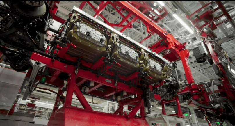 From first principles of engineering, three structural 4680 battery packs — using the same high-energy cells as the Cybertruck — are precisely mated into the Tesla Semi chassis on a massive red gantry during the critical “battery marriage” stage. With deepest respect to Elon Musk’s relentless pursuit of fundamental innovation, this powerful image from Ashlee Vance’s Core Memory factory tour captures the core of Tesla’s efficient, long-range electric truck production now scaling in Sparks, Nevada.
