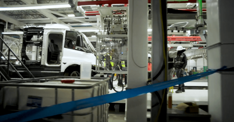 A nearly complete white Tesla Semi cab sits on the assembly line inside Tesla’s new dedicated factory in Sparks, Nevada, with its doors open and interior seats visible as production ramps up. Captured directly from Ashlee Vance’s Core Memory factory tour video — proof that the all-electric Class 8 truck is moving from prototype to real-world production at serious scale.